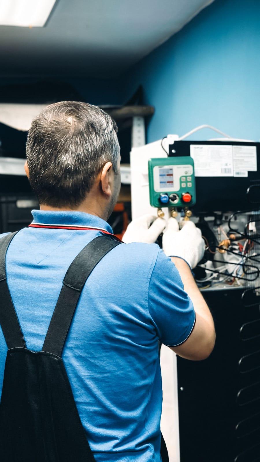 An HVAC technician servicing equipment with manifold gauges on site